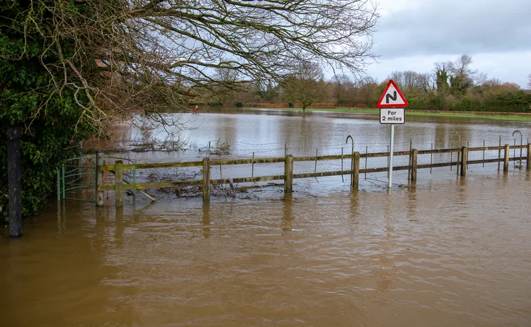 River Avon Lacock flooding across road with road sign after storm Henke