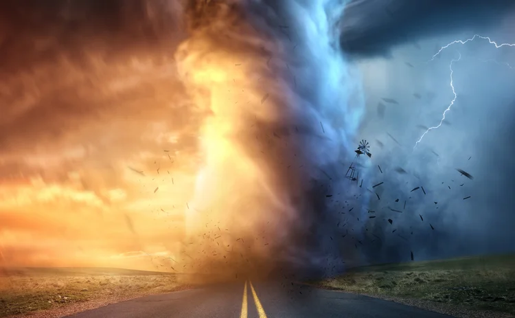 A powerful supercell storm at sunset producing a huge and destructive tornado touching down on a highway road