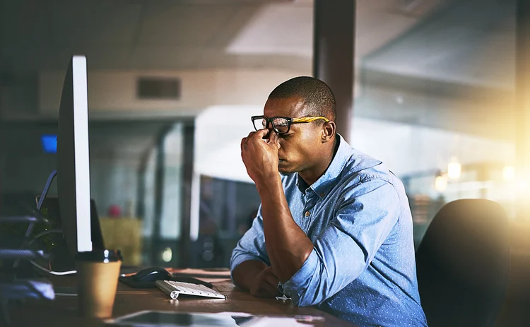 Shot of a young businessman experiencing stress during late night at work