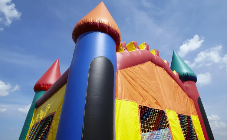 Stock photo of the top half of a children's inflatable bouncy castle with a blue sky and clouds.