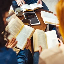 Diverse group of friends discussing a book in library.