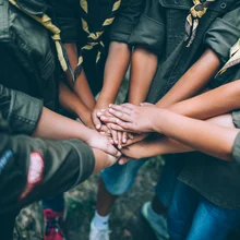 Group of young scouts joining hands together, showing their unity.