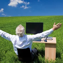 A businessman sat at a desk in a green pasture A businessman sat at a desk in a green pasture